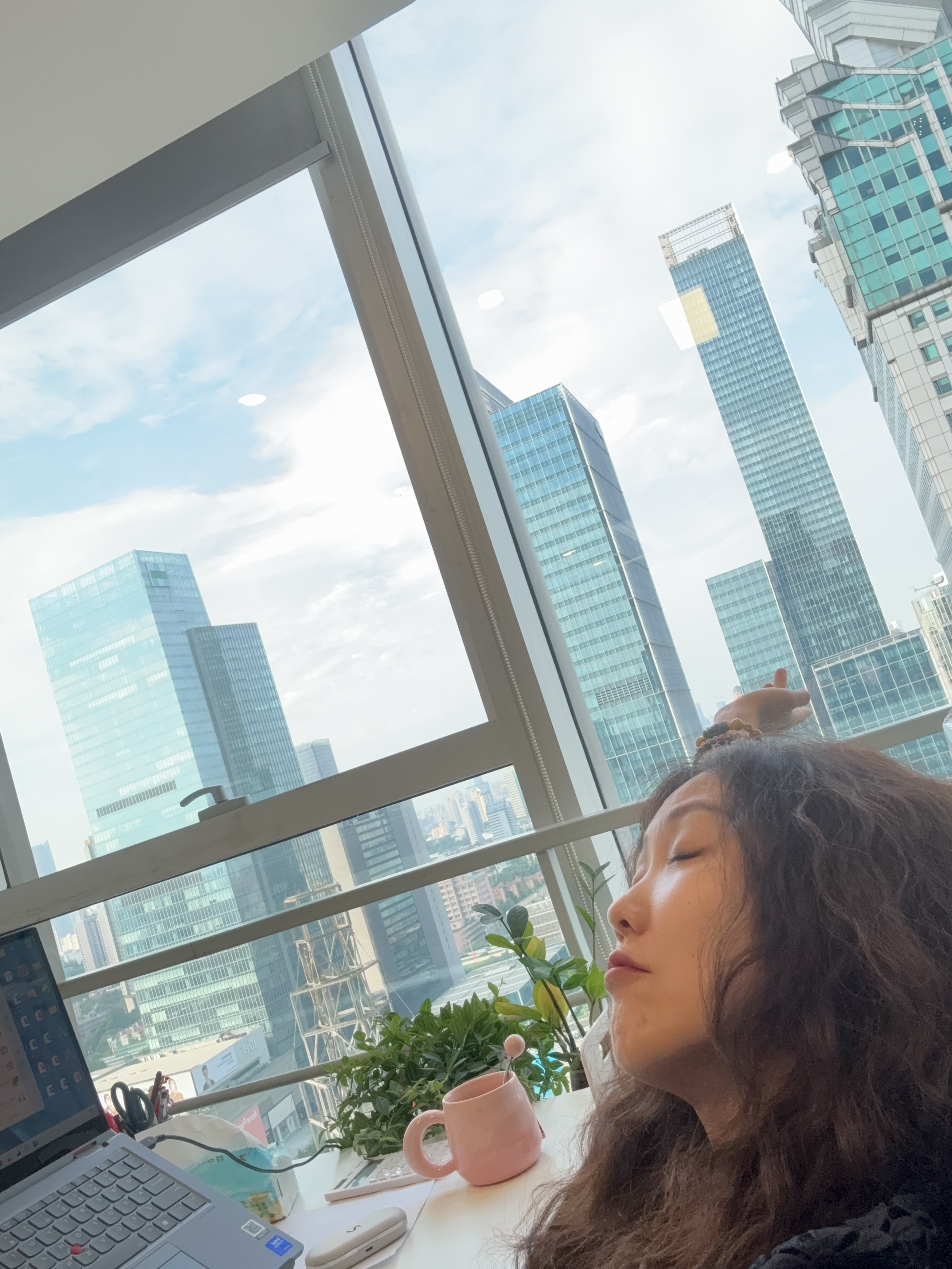 A quiet pause at a desk beside a bright city window